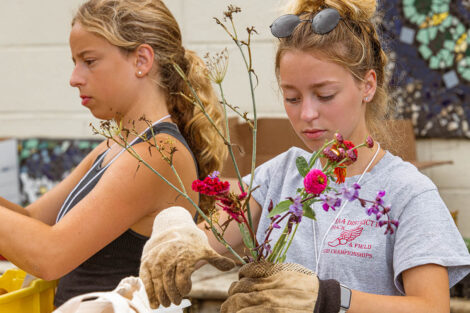 two students wearing work gloves create flower bouquets