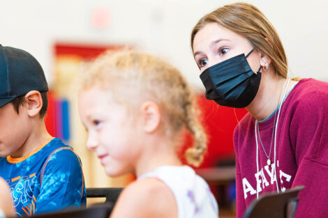 a Lafayette student wearing a mask sits with two young children