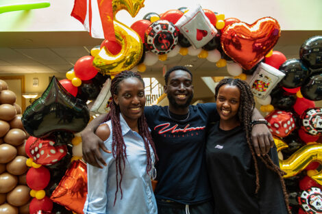 Students smile, surrounded by red and gold balloons.