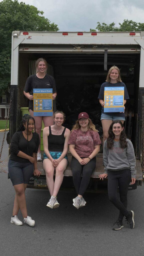 2022 Sustainability Impact Fellows and Sustainability interns sitting in the back of a moving truck carrying items to West Ward Sale