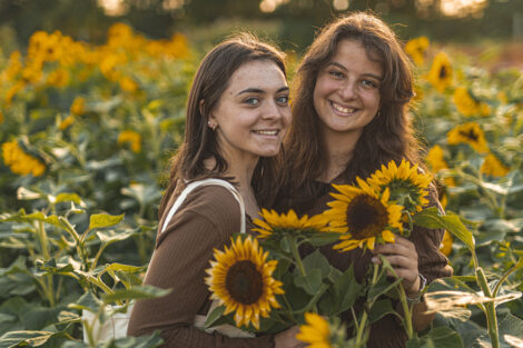 Two students smile with sunflowers.