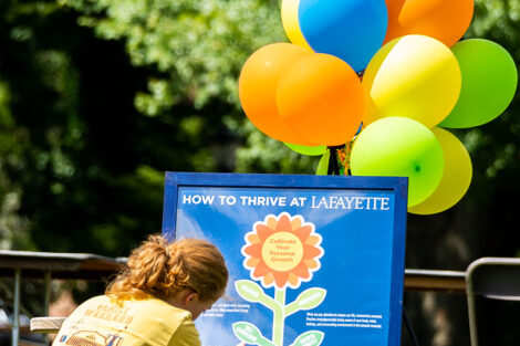 A student sits in front of a poster for Thrive.