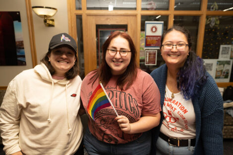 Three students display a rainbow flag during the National Coming Out Day Celebration and Resource Fair.