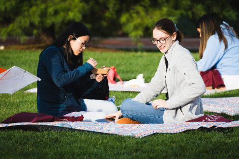 Two students eat food on a blanket on the Quad.