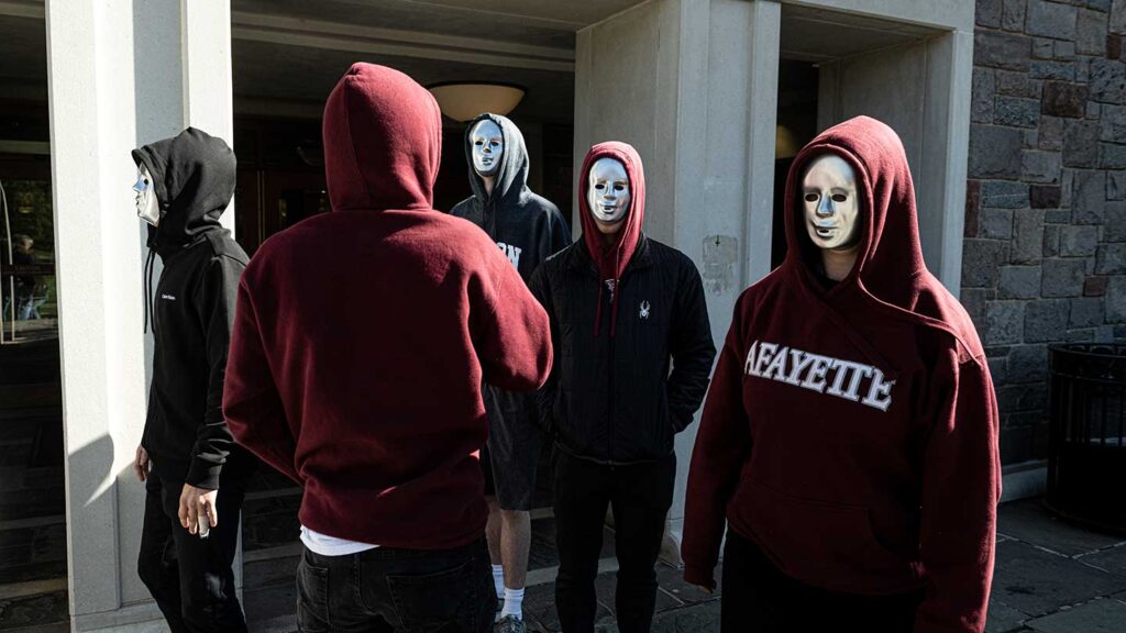 Students in Michael O'Neill's FYS course wearing silver masks and standing outside of Farinon Student Center as part of robot performance