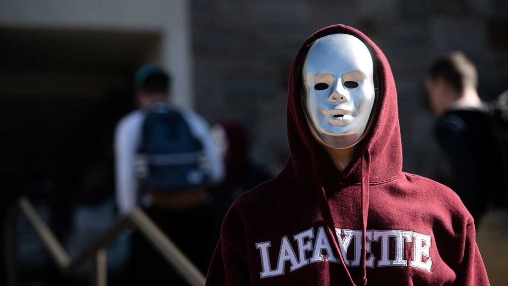 Students in Michael O'Neill's FYS course wearing silver masks and standing outside of Farinon Student Center as part of robot performance