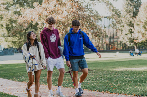 A group of students laugh while walking on a brick path of the Quad.