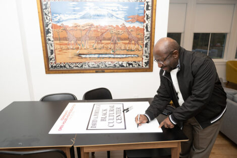 Prof. Rex Ahene signs a sign for the Lafayette community members gather at the Portlock Black Cultural Center Open House and Celebration.
