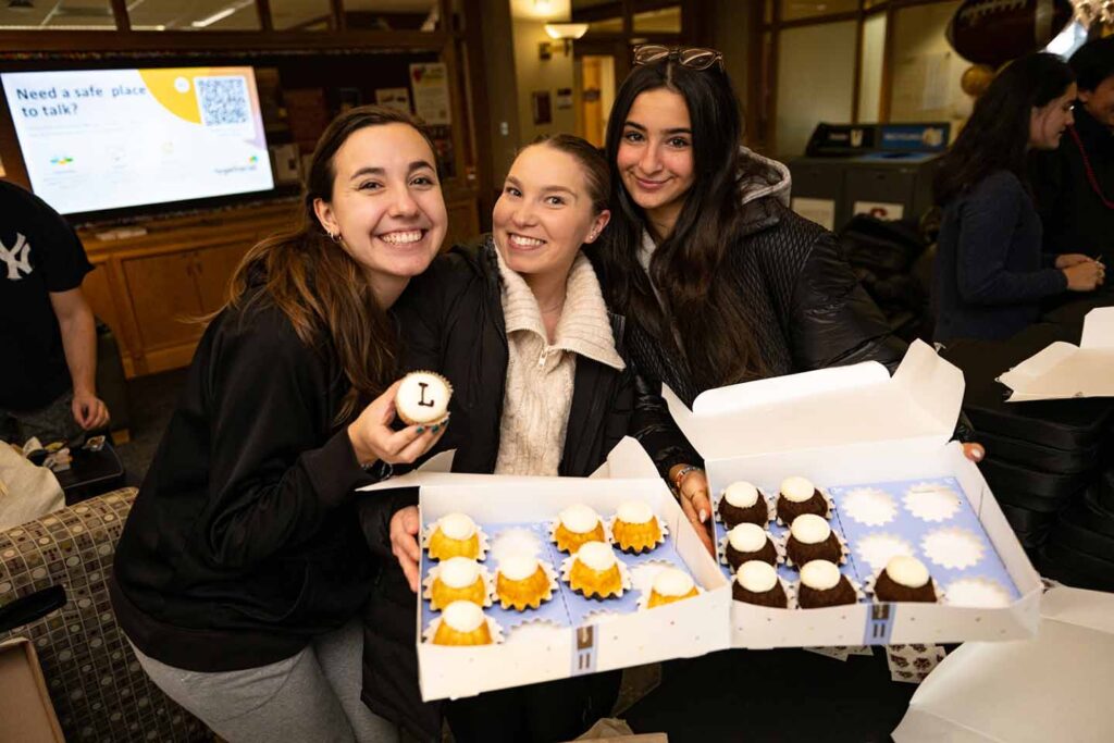 Three students pose with cakes in Farinon Student Center