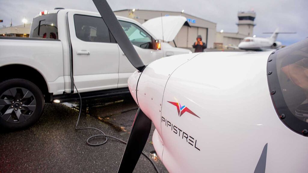 Close-up shot of Pipistrel Alpha Electro plane being charged by a Ford F150 Lightning pickup truck via charging cable