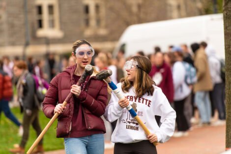 Two students carry sledgehammers on the Quad.