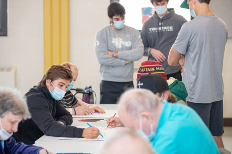 Student volunteers, masked, create art with people at Gracedale Nursing Home.