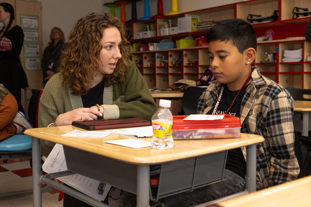 A Lafayette student speaks to a child in a classroom.