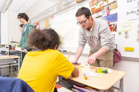 A Lafayette student assists a child in a classroom.