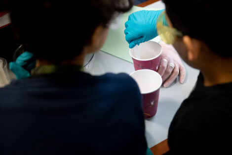 Students stir material in a paper cup.