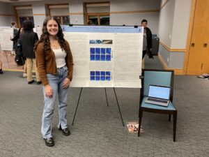 Rachel Giunta ’23 stands by a poster that shares the findings from this research.