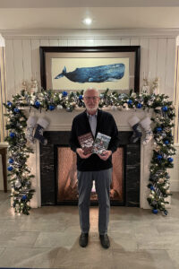 Rick Moore smiles, holding two books.