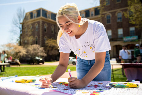 A student draws at a table in front of Pardee Hall.