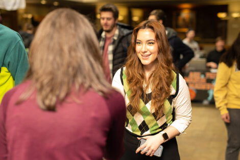 A student speaks to staff, smiling during Founders' Day