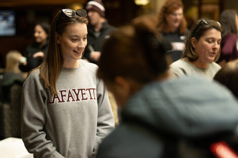 Staff members smile while talking to students inside of Farinon College Center during Founders' Day