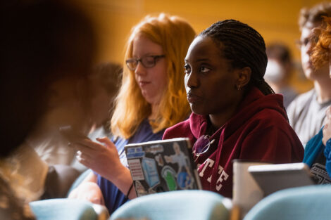 Students in an auditorium listen to a speaker.