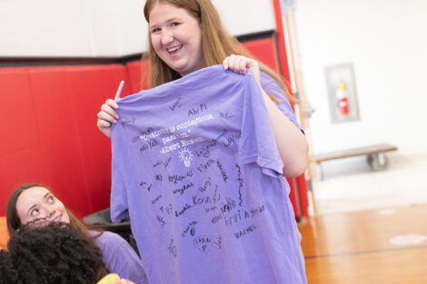 A Lafayette student holds up a t-shirt that has been signed by attendees.