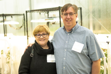 Heidi '91 and Daniel Hanson are standing arm in arm at the new greenhouse