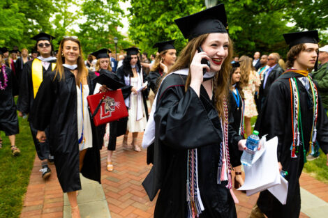 A graduate smiles, on their phone.