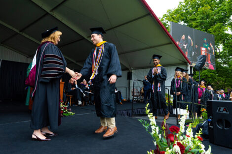 A student shakes President Hurd's hand on stage.