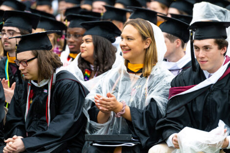 A graduate claps in the crowd.