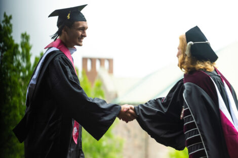 A student shakes President Hurd's hand on stage.