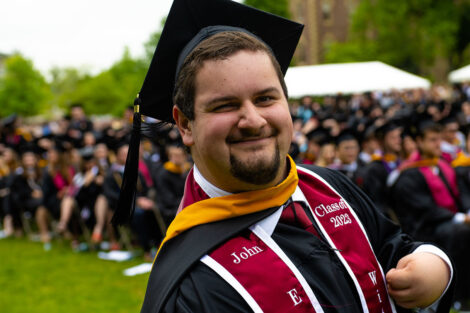 A graduate smiles in the crowd.