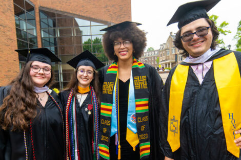 Students smile, wearing their caps and gowns.