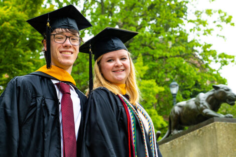 Students smile, wearing their caps and gowns.