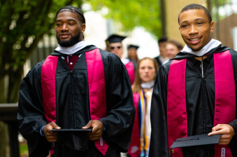 Students walk, wearing their caps and gowns.