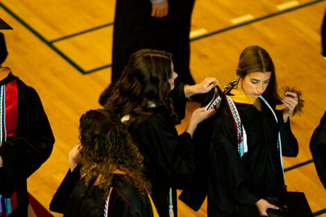 A student gets their robe put on.