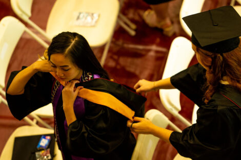 A student gets their robe put on.