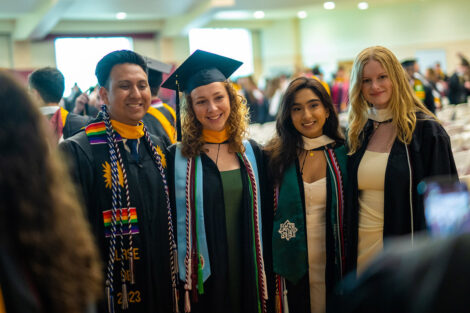 Students smile in their caps and gowns.