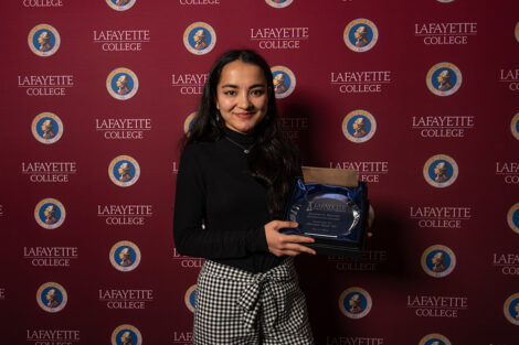 Mahdia Azizi '24 smiles, holding an award.