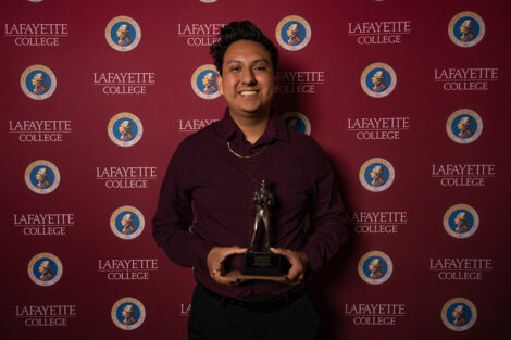 Luis Tapia Morales '23 smiles, holding an award.