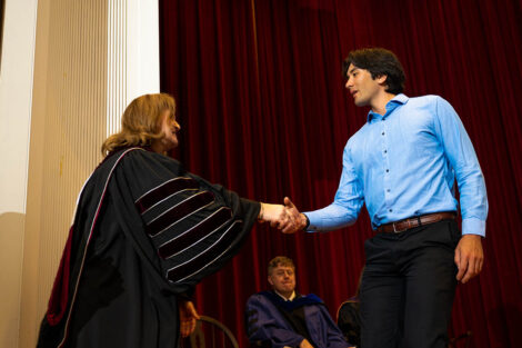 President Nicole Hurd shakes hands with a student.