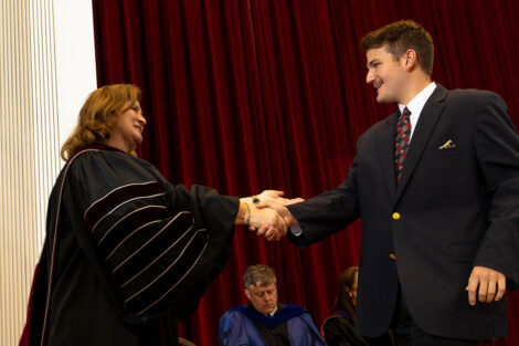 President Nicole Hurd shakes hands with a student.