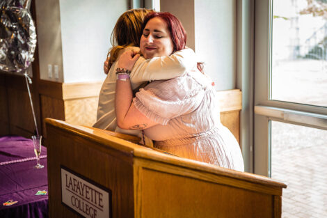 President Nicole Hurd and Meredith McGee hug in front of a podium.