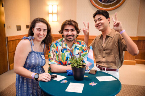 Three students smile at a table.