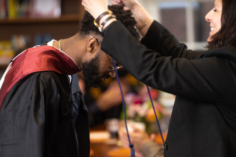 A staff member gives a student their multicultural stole.