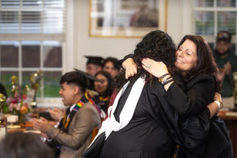 A staff member smiles as they hug a student.