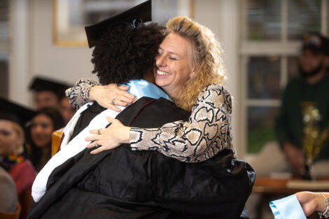 Janine Block hugs a student wearing a cap and gown.