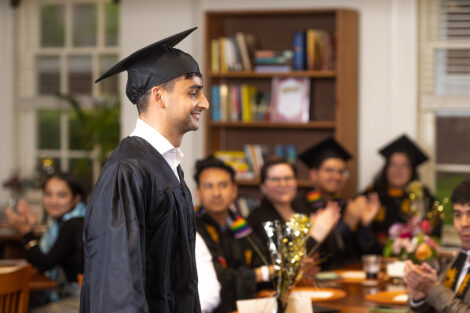 A student in a cap and gown smiles.