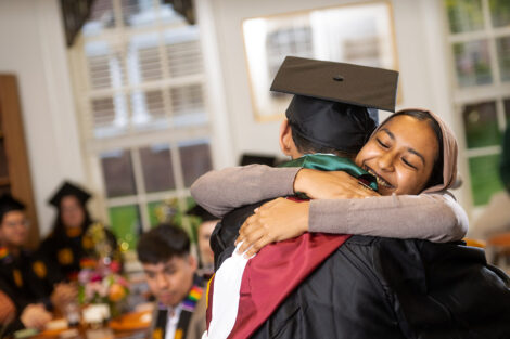 Two students embrace in smiles.