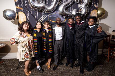 Karina Fuentes and Rob Young '14 smile, surrounded by students wearing multicultural stoles.